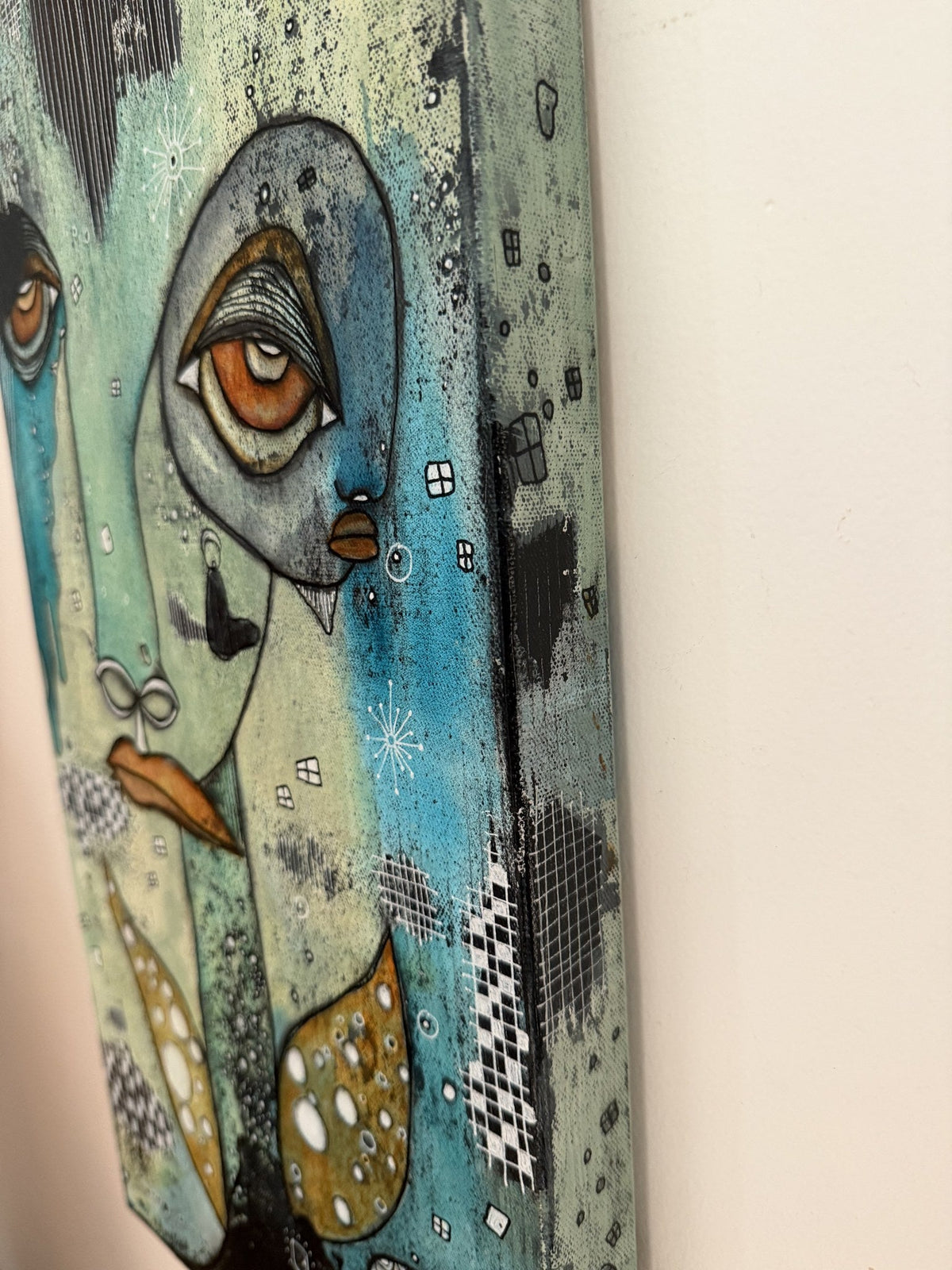 Angled side view of the canvas showing its depth, painted edges, and a profile face with dangling earring
