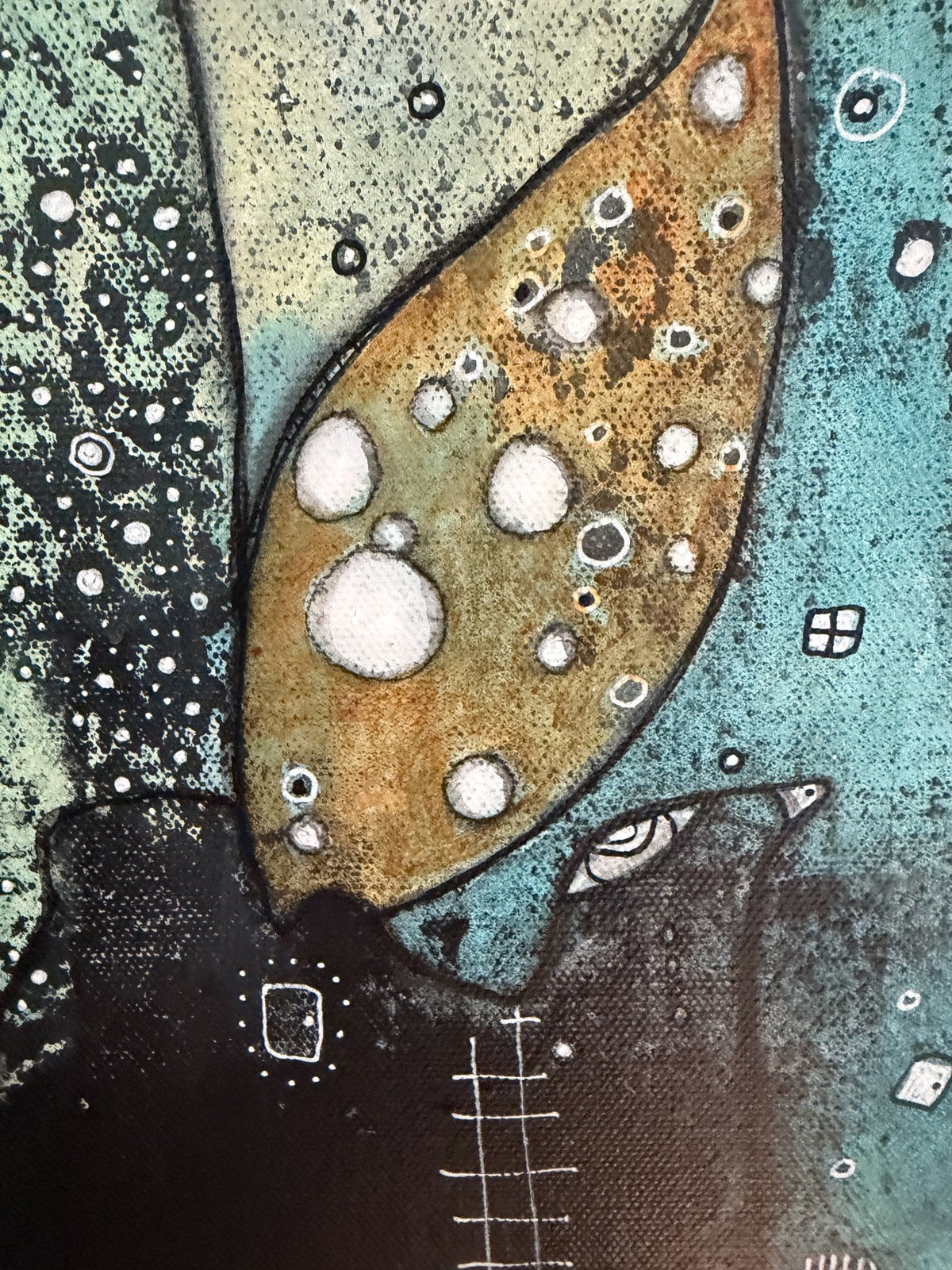 Close-up detail of a gold wing-like shape textured with white circular bubbles and dotted patterns
