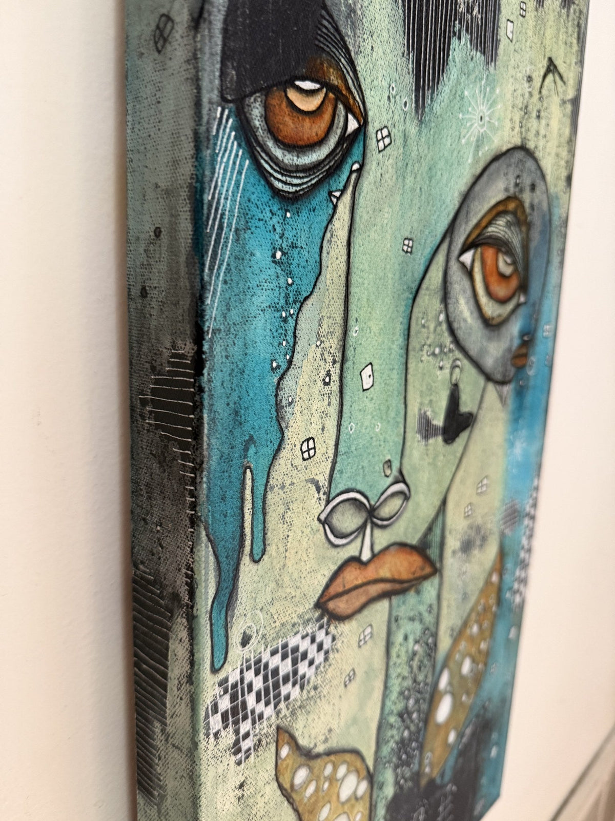 Angled view of canvas edge showing painted depth, a teal tear drip, and checkerboard pattern detail