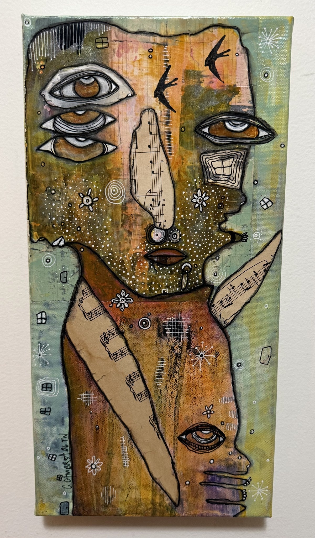 Side angle of canvas on wall showing stacked eyes, music-note face, and sheet-music garment collage details