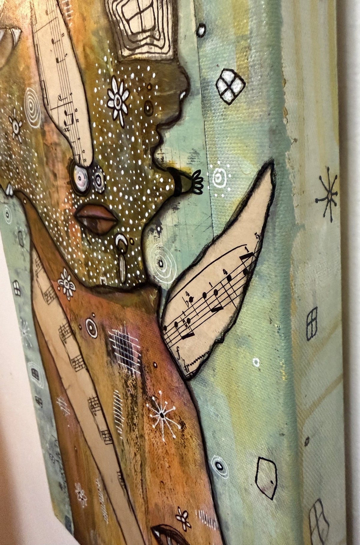 Detail of dotted face profile with sheet-music wing shape, small hand, and swirling star accents