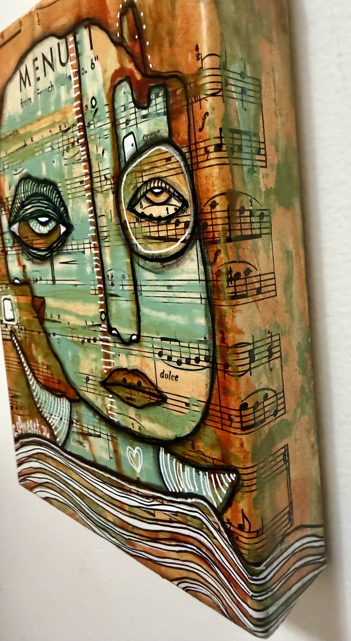 Angled side view showing the canvas depth and thick textured layers of paint and sheet music collage