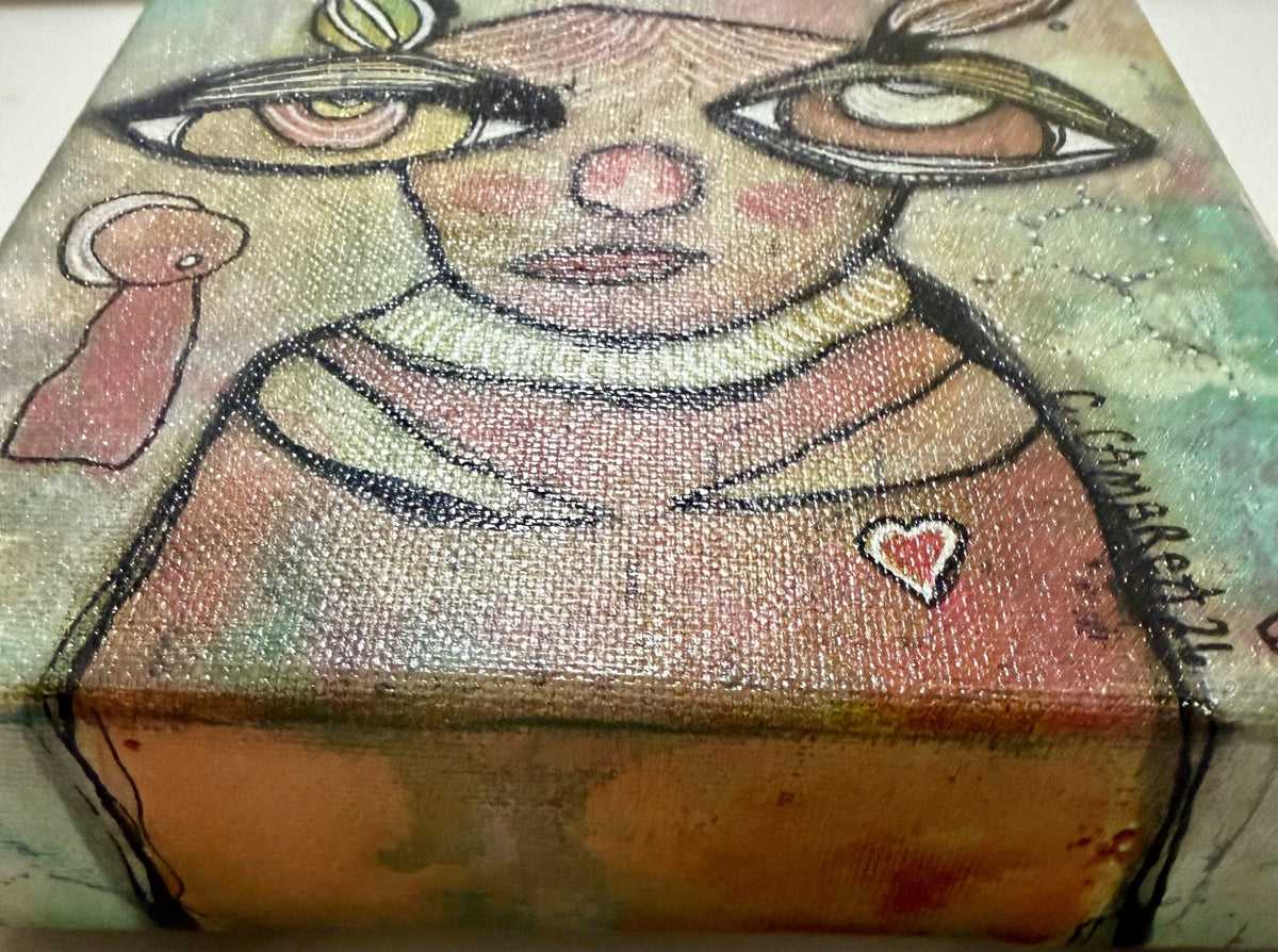 Close-up detail view from above of the face, red heart accent, and the artist's signature along the canvas edge.