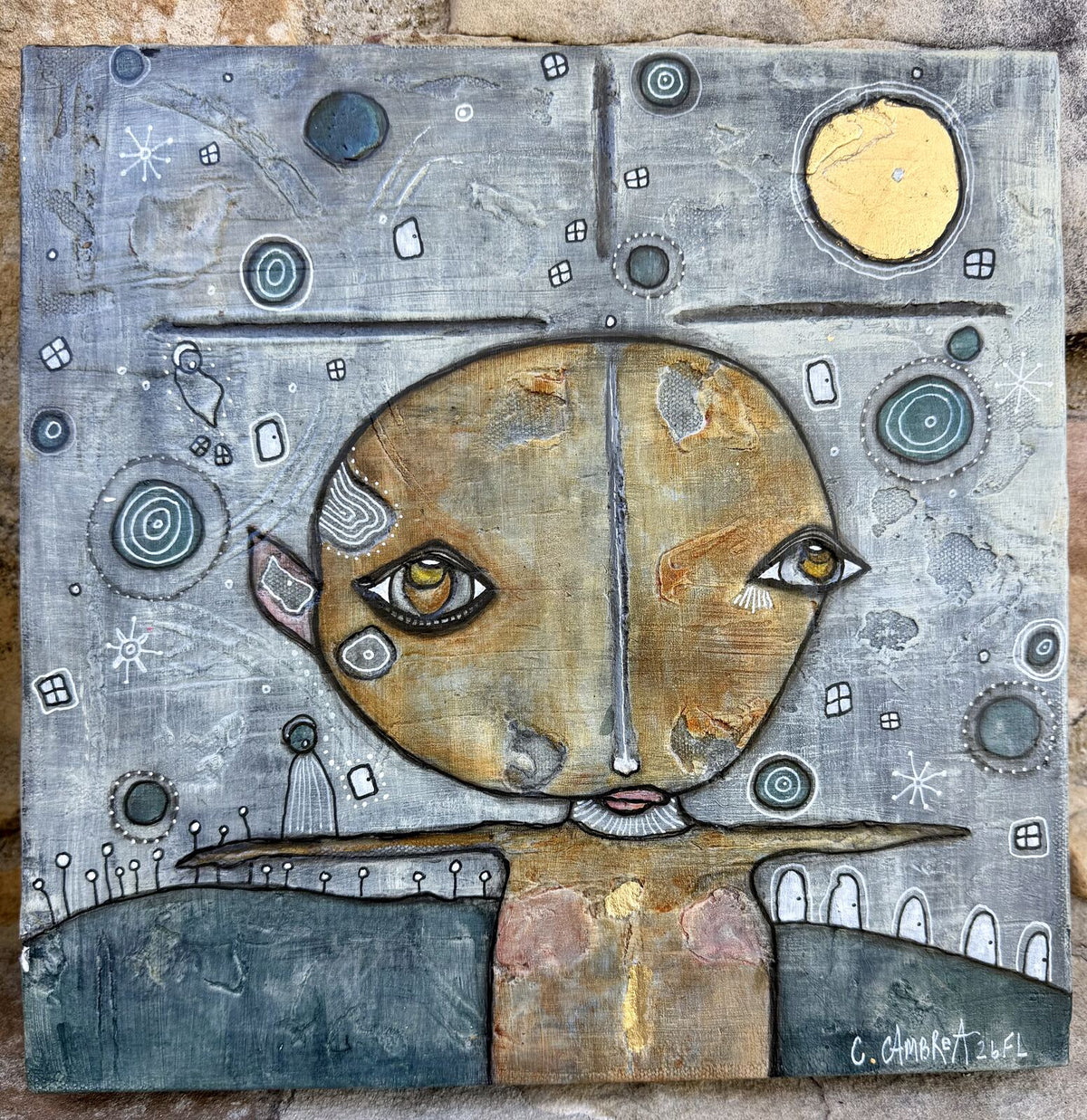 Full front view of "Under The Moon" mixed media painting showing a round golden face beneath a gold leaf moon, with a figure and fence silhouette below
