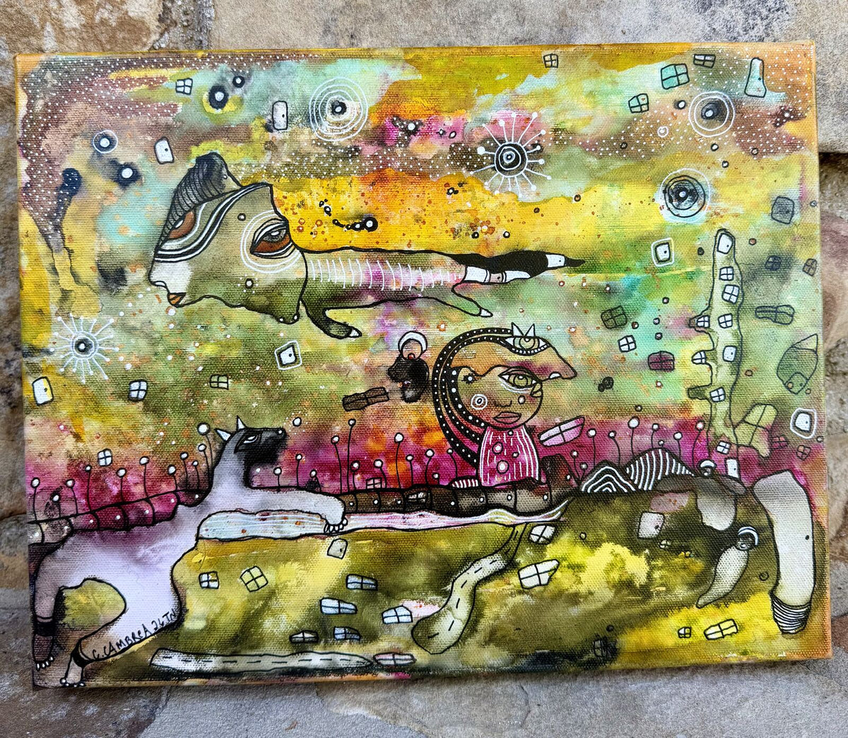 Full front view of "The In Between" mixed media painting showing a floating goat-like creature above a girl figure with a spiral crown, a cat, and colorful dreamlike landscape